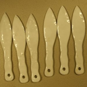 Bildet viser 6 hvite porselenskniver med hull øverst i skaftet.